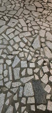 a close-up of a crazy paving stone floor featuring irregularly shaped granite and marble tile fragments set in mortar.