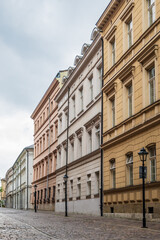 Tall, ornate facades with multiple windows characterize these historic buildings, showcasing classic European architecture on a quiet street in the old town of Krakow, Poland. © Danica Chang