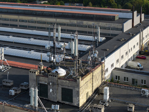 Aerial view of telecommunication towers and antennas installed on the rooftop of a large industrial building with HVAC units in Krakow, Lesser Poland Voivode, Poland.