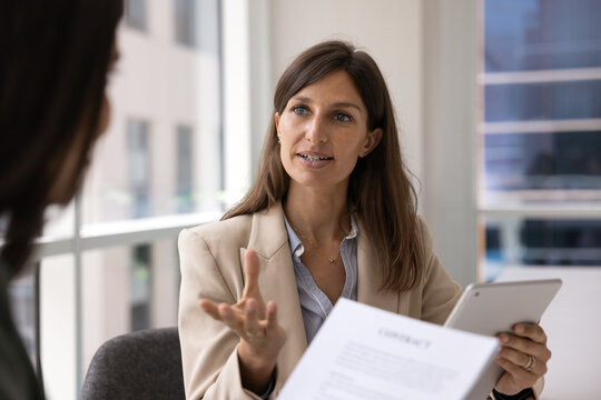 Confident Hispanic female bank manager or legal advisor explaining contract details to customer guiding through business conditions discussing commercial agreement benefits at corporate office meeting