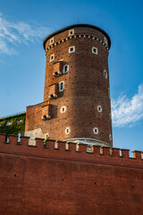 Low-angle view of Baszta Sandomierska, a medieval brick tower with small windows and strong fortifications, part of Wawel Castle complex in Krakow, Poland. © Danica Chang