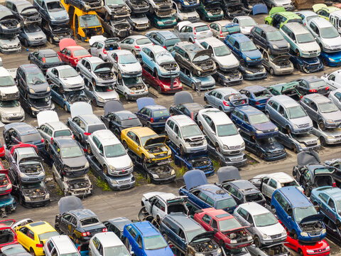Aerial view of end of life vehicle recycling facility with rows of stacked cars and open hoods in a scrapyard Gdansk, Pomeranian Voivodeship, Poland.