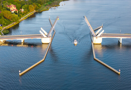 Aerial view of the Sobieszewo drawbridge opening to allow a small boat to pass through the river in Gdansk, Pomeranian Voivodeship, Poland.