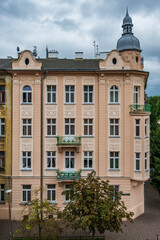 An elegant corner building showcasing intricate architectural details, rounded bay windows, small balconies, and a distinctive domed turret in Krakow, Poland. © Danica Chang