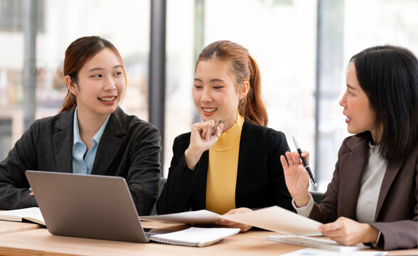 Asian Businesswomen Smiling and Discussing Project with Laptop in Office