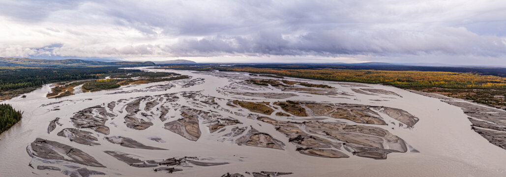 Aerial view of the Tanana River with its braided channels, sandbars, and surrounding autumn-colored boreal forest under a cloudy sky in Yukon-Koyukuk Census Area, Alaska, United States.