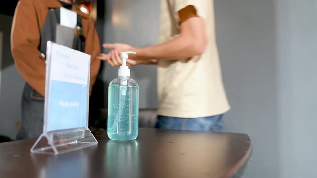 A barbershop counter holds a hand sanitizer bottle beside a countertop display. The barbershop scene shows a pump bottle with clear liquid and a transparent acrylic stand on the dark worktop.