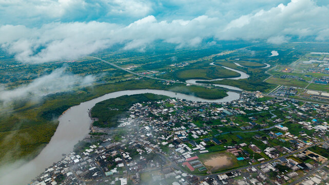 Aerial view of the winding Kwa Ibo River flowing past residential areas and lush greenery under a cloudy sky in Kwa Ibo, Akwa Ibom, Nigeria.
