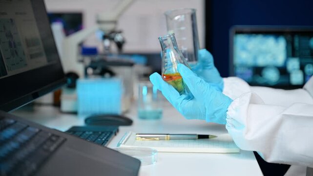 Focused scientist in hazmat suit analyzes brain scan data on high-tech monitors and writes clinical research notes