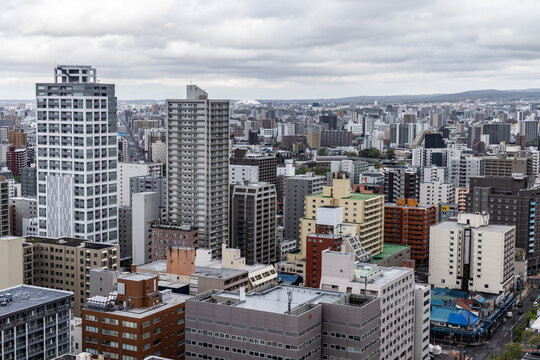 Aerial view of Sapporo city skyline featuring dense high-rise residential and commercial buildings under a cloudy sky in Sapporo, Hokkaido, Japan.