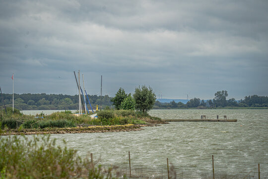 Eine Reihe von Segelbooten, sicher vert&auml;ut an einem Holzsteg im Hafen des D&uuml;mmer Sees, ist fast vollst&auml;ndig unter leuchtend blauen Planen verborgen. Ihre Masten ragen wie ein grafischer Wald in den be