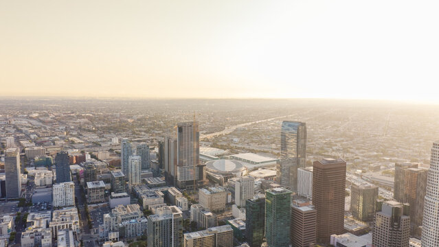 Aerial view of the Los Angeles skyline with modern skyscrapers, dense urban architecture, and city streets bathed in golden hour light Los Angeles, California, United States.