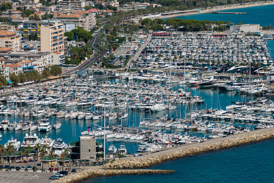 Aerial view of Port Vauban in Antibes filled with numerous yachts and boats, bordered by stone breakwaters and the coastal urban landscape of Antibes, Provence-Alpes-Cote d'Azur, France.