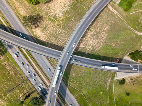 Aerial view of a highway interchange in Brackenfell with vehicles traveling on intersecting roads surrounded by grassy fields in Cape Town, Western Cape, South Africa.