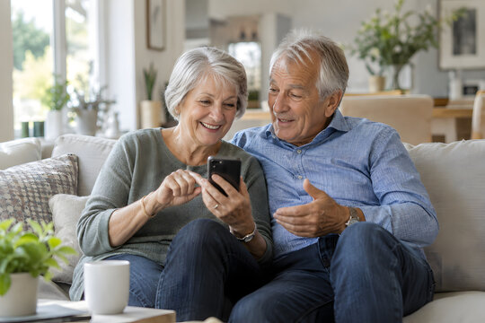 Older couple using a smartphone together while sitting at home