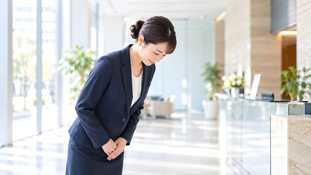 Businesswoman bowing politely in a bright modern office lobby