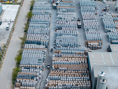Aerial view of the industrial yard in Philippi featuring rows of stacked concrete blocks and paving materials with trucks in the facility in Cape Town, Western Cape, South Africa.