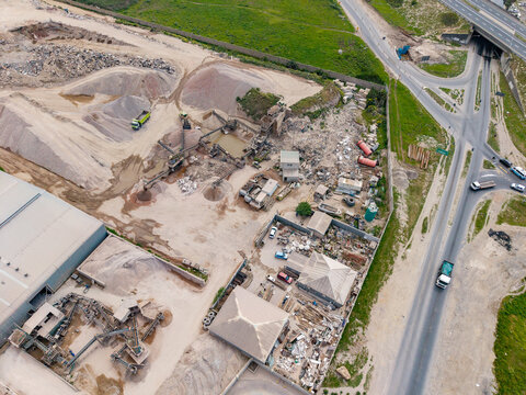 Aerial view of the Philippi industrial quarry site with piles of sand, gravel, and heavy machinery operating near a highway in Cape Town, Western Cape, South Africa.