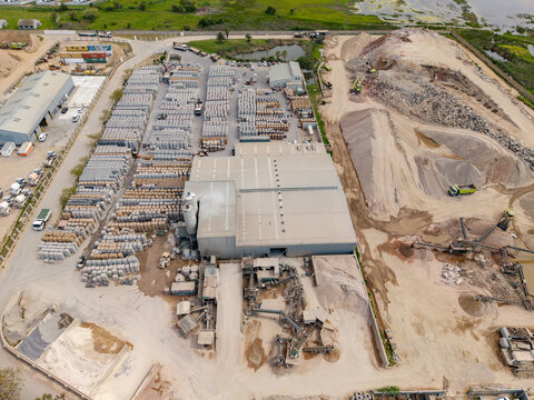 Aerial view of the Philippi industrial site with large piles of sand, gravel, conveyor belts, a warehouse, and rows of stacked materials in Cape Town, Western Cape, South Africa.