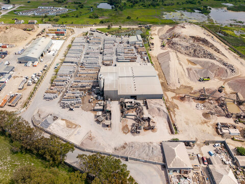 Aerial view of the Philippi industrial site featuring large stockpiles of gravel, rows of stacked concrete products, and warehouse buildings in Cape Town, Western Cape, South Africa.