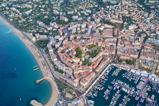 Aerial view of the historic Le Suquet district, the bustling marina filled with yachts, and the sandy coastline of the Mediterranean Sea in Cannes, Provence-Alpes-Cote d'Azur, France.