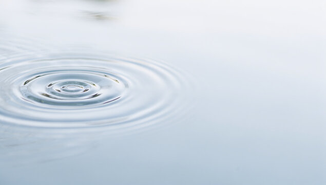Concentric water ripples and wave circles on a calm liquid surface with space for text