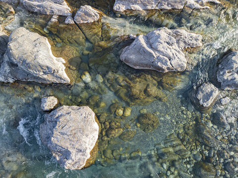 Aerial view of the clear waters of the Kiri River flowing over large smooth rocks and pebbles in Shkoder, Qarku i Shkodres, Albania.