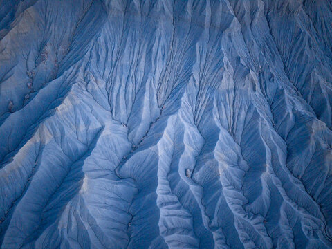 Aerial view of the intricate eroded ridges and deep gullies of the badlands, showcasing textured clay formations and natural patterns in Caineville, Utah, United States.