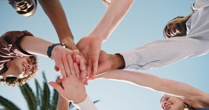People, unity and friends with hands together in park for mission, social cohesion or solidarity. Low angle, group or community piling with stack or blue sky for outdoor meeting, trust or support