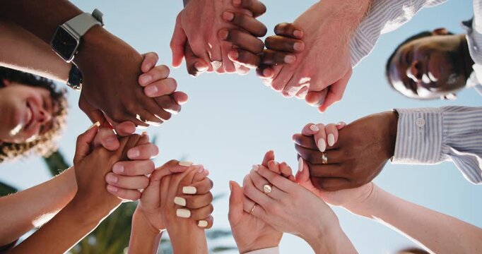 People, unity or holding hands together with group for social cohesion, inclusion or solidarity. Low angle, team or community with connection, support or trust for outdoor synergy or collaboration