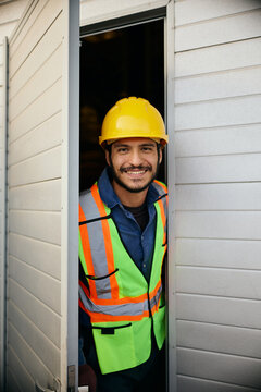 Happy blue collar worker at building doorway looking at camera.