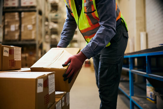 Close up of worker arranging shipment boxes while working in distribution warehouse.
