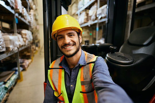 Happy warehouse logistic worker taking selfie and looking at camera.