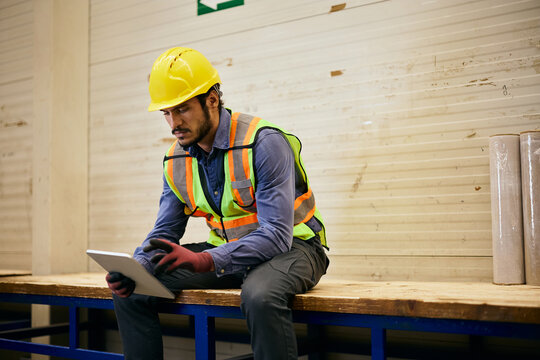 Blue collar worker using digital tablet while working in industrial facility.
