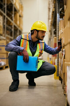 Warehouse employee inspecting packages while checking inventory in storage facility.
