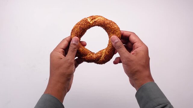 Hands breaking fresh turkish simit bread on white background in slow motion cinematic video clip