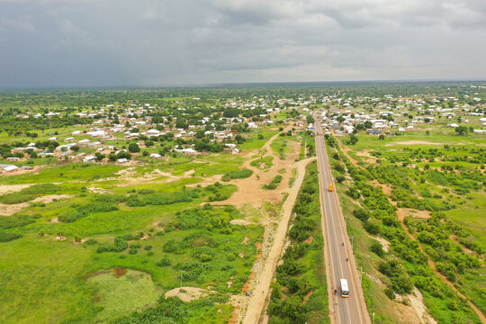 Aerial view of the town of Buipe with its scattered buildings, lush green vegetation, and a long road stretching through the landscape in Buipe, Savannah Region, Ghana.