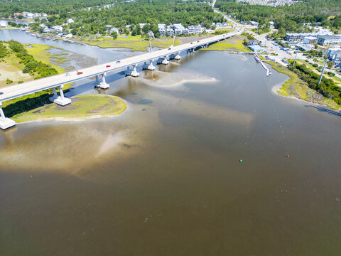 Aerial view of North Topsail Bridge spanning the waterway with surrounding marshlands, coastal vegetation, and nearby residential buildings in North Topsail Beach, North Carolina, United States.