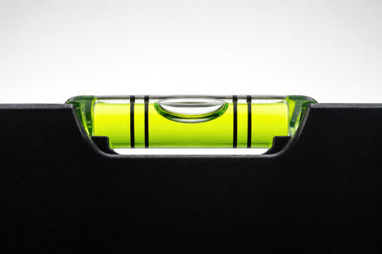 A high-resolution photorealistic macro product photograph of a transparent horizontal spirit level bubble vial resting above a smooth matte black surface