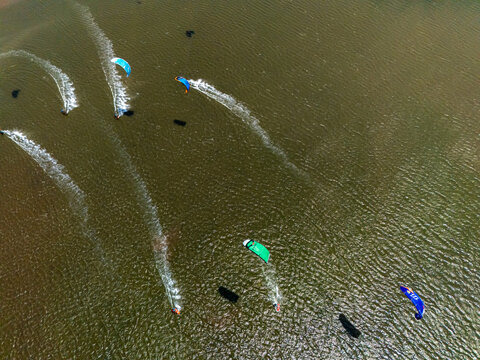 Aerial view of kitesurfers gliding across the water at Depok Beach, leaving white wakes behind them in Special Region of Yogyakarta, Indonesia.