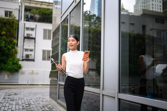 Young Asian Businesswoman Walking Outdoors with Coffee and Laptop