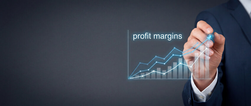 Businessman in a dark suit drawing an upward glowing line graph and bar chart representing increasing profit margins and financial growth on a virtual interface with copy space for text.