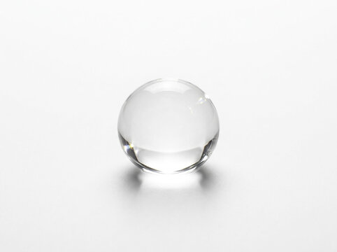 Transparent glass ball isolated on white background, clear crystal sphere with soft shadow, minimal optical glass globe object, smooth reflective orb for concept design and photography