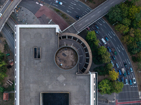 Aerial view of the brutalist architecture of the ICC Berlin featuring its distinctive circular roof structure and adjacent highway with traffic in Berlin, Berlin, Germany.
