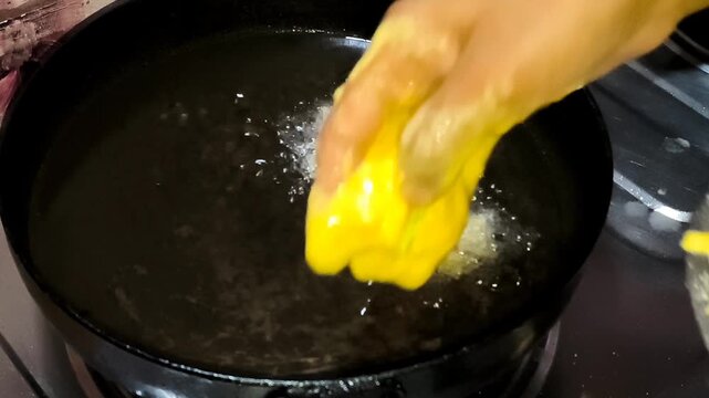 Hand Dropping Fresh Dough Batter into Hot Sizzling Oil for Frying
