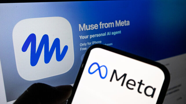 Smartphone displaying meta logo held against computer screen with muse from meta application branding.