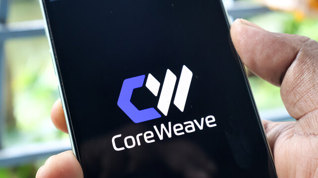 A close-up view of a smartphone screen displaying the CoreWeave company logo on a dark background.