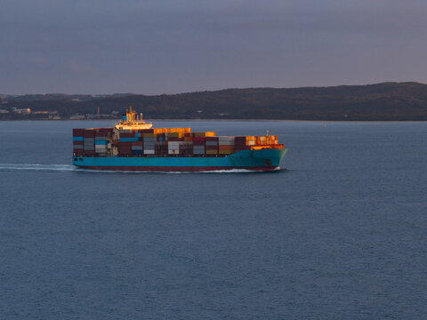 Aerial view of a cargo ship on the ocean in the last golden light of day