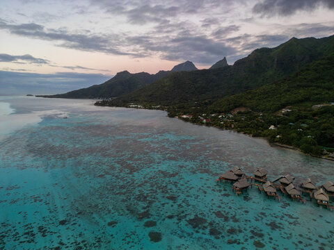 Aerial view of Sofitel Kia Ora Moorea Beach Resort with overwater bungalows, turquoise lagoon, coral reefs, and lush mountains in Moorea-Maiao, Windward Islands, French Polynesia.