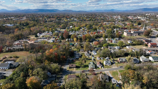 Aerial view of the town of Lynchburg with colorful autumn foliage, residential houses, and distant mountains under a blue sky in Lynchburg, Virginia, United States.